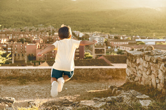 Ni&ntilde;o peque&ntilde;o saltando alegremente al atardecer con vistas a un pueblo