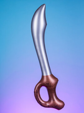 Close-up of an inflatable sword with an ornate handle on a purple background, showcasing its vibrant colors and detailed design.