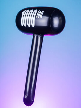 Close-up of an inflatable hammer-shaped toy with a handle on a purple background