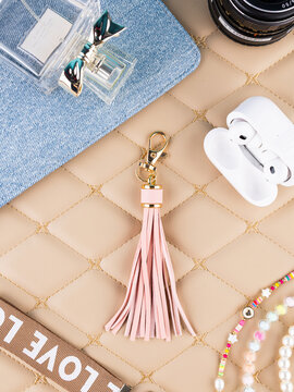 Close-up of a leather tassel-shaped keychain on a beautiful table with women&rsquo;s accessories. Elegant and charming accessory