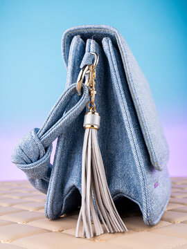 Close-up of a leather tassel-shaped keychain  on a  blue bag. Elegant and charming accessory