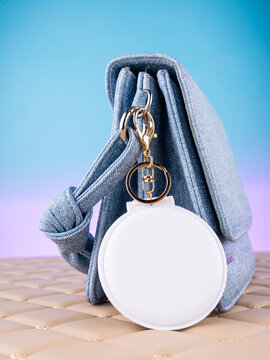 Close-up of a leather mirror-shaped keychain on a  blue bag. Elegant and charming accessory.