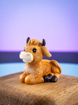 Close-up of a cute miniature cow figurine in an interior setup on a purple background