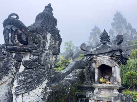 Stone shrine with offerings and misty candi bentar gates at Pura Lempuyang, Gates of Heaven, Karangasem, East Bali, Indonesia.