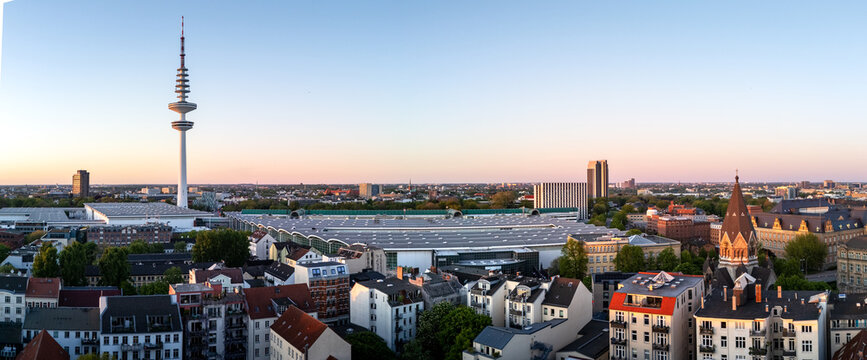 Aerial view of Messehallen exhibition center and the Heinrich-Hertz-Turm tower rising above the dense urban landscape of residential buildings in Hamburg, Hamburg, Germany.
