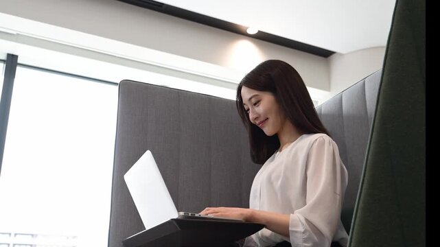 コワーキングスペースでノートパソコンを使って仕事をする20代の日本人女性