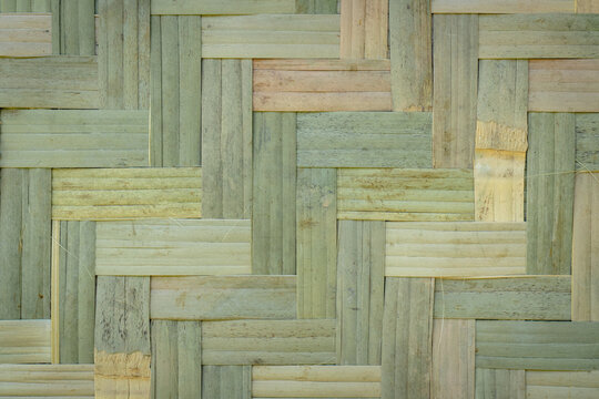 Close-up of woven bamboo wall featuring an interlocking geometric pattern, highlighting natural material, handcrafted design, and rustic texture for background use.