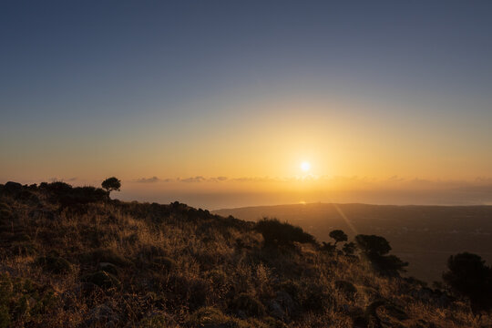 Rocky hillside of Mount Edheri with wild vegetation and scenic view of Malia coastline on Crete, Greece at golden sunset