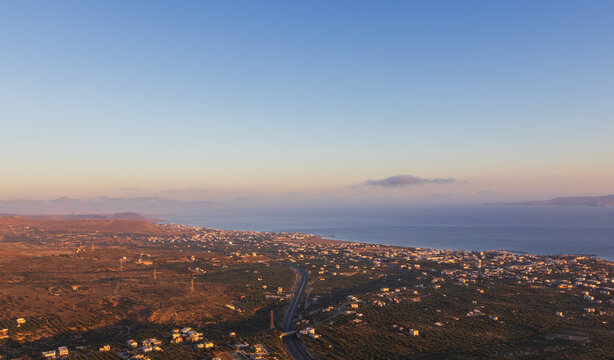 Panoramic high angle aerial view of Kato Gouves town and coastline on Crete, Greece from Mount Edheri at sunset