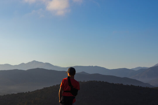 Close-up rear view of an 11-year-old boy with an arm brace looking at the beautiful mountain range in Crete