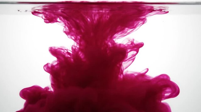 Large red ink cloud expanding underwater on white.
