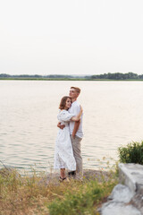 Fototapeta premium Young couple embracing by the water's edge on a warm summer day