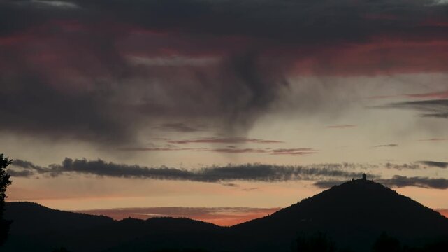 Silhouette of Haut Koenigsbourg castle at sunset. Orange clouds scroll by in timelapse.