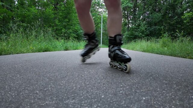 The camera focuses on roller skates as they open and prepare for use. The background shows a natural scene with green trees. A person is about to start skating.