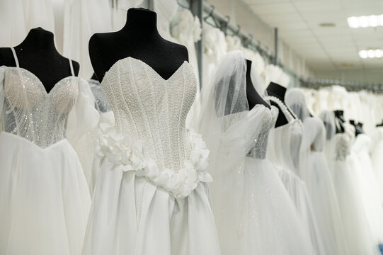 Elegant white wedding dresses on mannequins in bridal boutique display