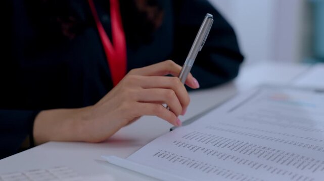 Professional hand pen document paper business meeting writing closeup office person reviewing contract report paperwork at desk with formal suit red lanyard woman workplace focus