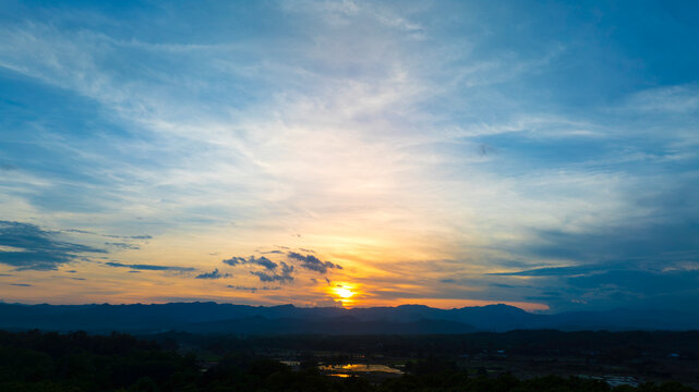 Golden Sunset Over Mountain Range with Dramatic Blue Sky Landscape Background