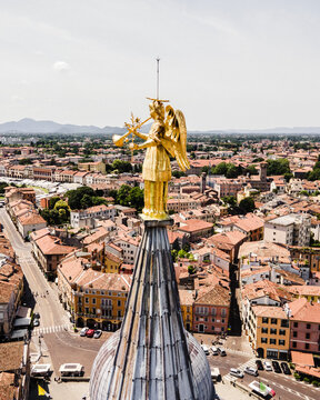 Aerial view of the golden angel statue atop the spire of the Basilica of Saint Anthony of Padua, overlooking the historic city rooftops and streets in Padua, Veneto, Italy.