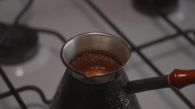 Coffee boiling in copper cezve on gas stove