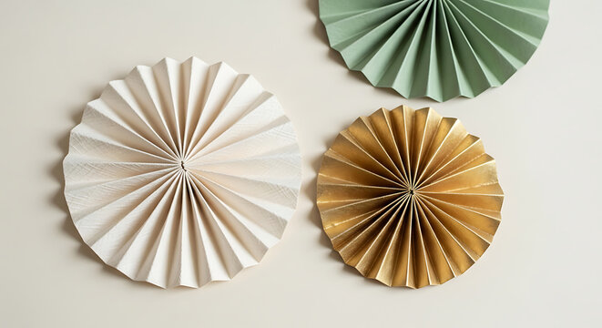 Three decorative paper fans in cream, gold, and sage green arranged on a neutral background