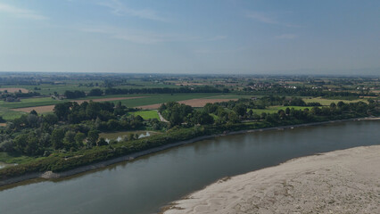 Fototapeta premium Po River's dramatic low water level showcasing extensive dry riverbed and exposed sand bars, illustrating the severe drought and ongoing water crisis impacting the Italian landscape and agriculture