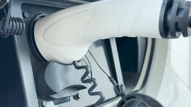 An electric vehicle plug connects to a port. This efficient interaction inspires hope for a sustainable future, evoking feelings of progress and responsibility for our environment.