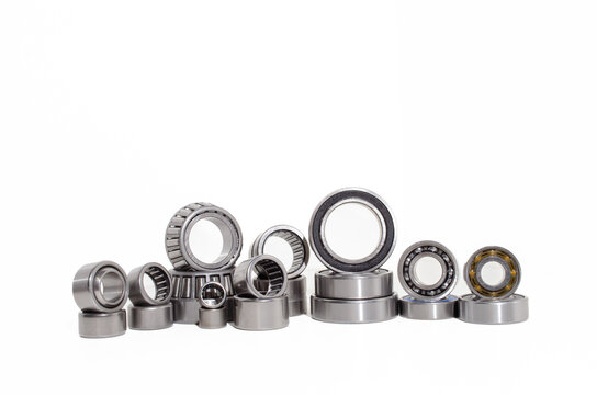 A collection of industrial ball bearings, roller bearings, tapered roller bearings, and needle bearings arranged in a row on a white background.