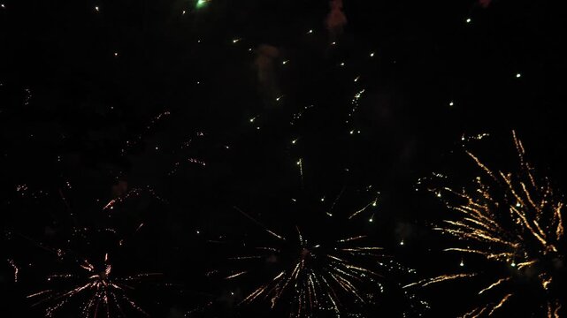 spectacular fireworks display sequence in night sky aerial perspective with bright lights and celebratory mood for holiday new year celebration event in red yellow green.