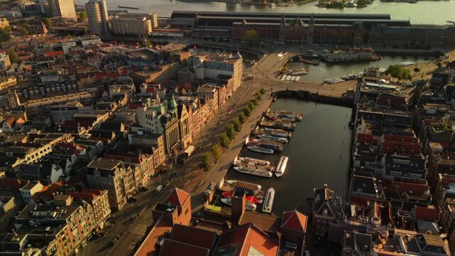 Drone flies above Amsterdam canal harbor lined with tour boats as historic city center comes into view