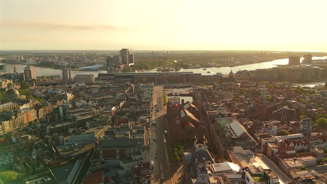Aerial drone flies above central Amsterdam toward the IJ waterfront revealing dense historic cityscape and urban fabric
