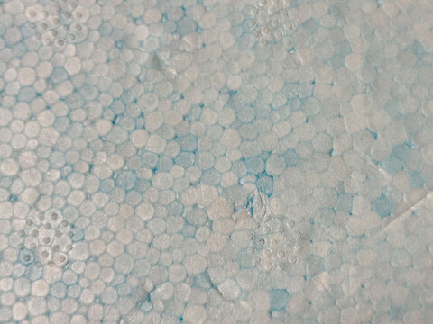 Vista en primer plano de la textura de poliestireno con peque&ntilde;as burbujas blancas sobre fondo azul en horizontal