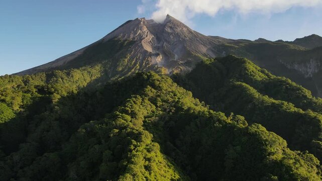 Aerial view of Mount Merapi Volcano at Sunrise, Yogyakarta, Indonesia. Mount Merapi illuminated by sunrise, with lush tropical forest covering its lower slopes and dramatic volcanic scenery