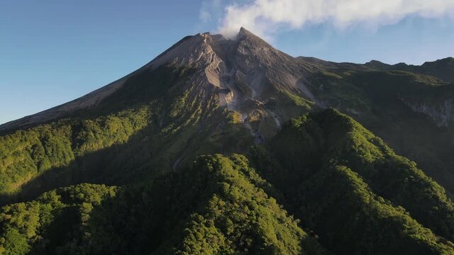 Aerial view of Mount Merapi Volcano at Sunrise, Yogyakarta, Indonesia. Mount Merapi illuminated by sunrise, with lush tropical forest covering its lower slopes and dramatic volcanic scenery