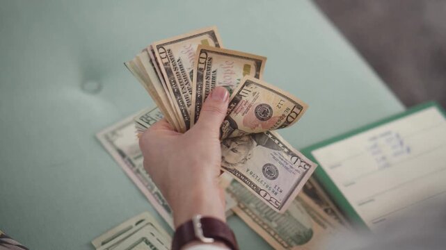 Person Counting US Dollar Banknotes in a Professional Office Setting Close Up