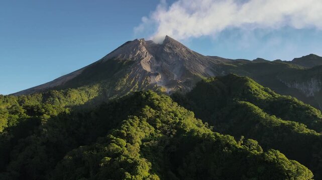 Aerial view of Mount Merapi Volcano at Sunrise, Yogyakarta, Indonesia. Mount Merapi illuminated by sunrise, with lush tropical forest covering its lower slopes and dramatic volcanic scenery