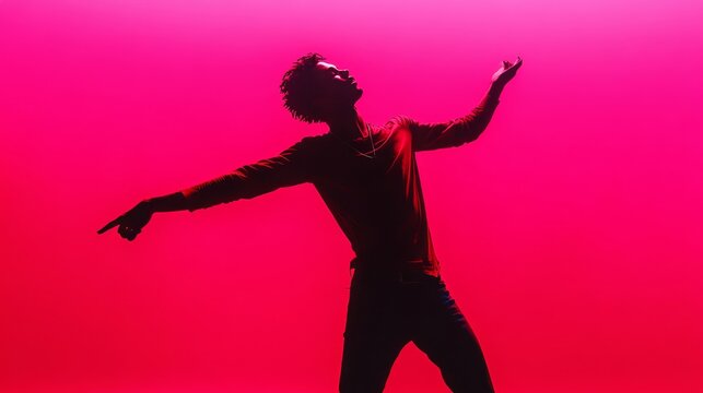 Dynamic silhouette of a young man dancing expressively against a bold and vibrant pink background.