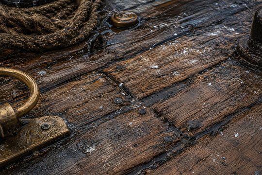 Weathered wooden boat deck close up with rope and metal hardware showing worn planks salt stained texture nautical detail maritime history rustic travel surface and seafaring adventure