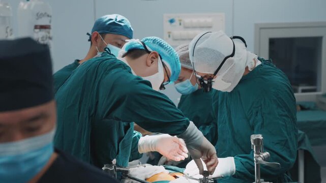 Group of surgeons performing a surgery procedure in a clinical operating room, carefully handling instruments and maintaining a steady workflow in sterile setup of a modern hospital environment. Steri