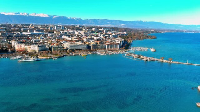 Aerial view of the Geneva waterfront along Quai du Mont Blanc on Lake Geneva, Switzerland, with hotels, a paddle steamer, the Paquis pier and snow capped Jura mountains on a clear winter day.