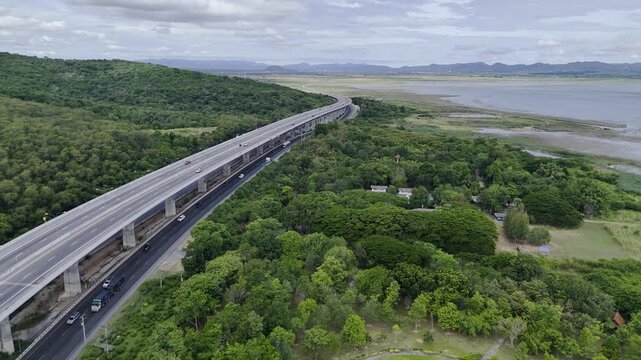Aerial view of highway running along river and green hills. Transportation, infrastructure, travel and logistics concept
