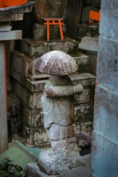 Traditional Japanese Stone Monk Statue with Miniature Torii Gate at Fushimi Inari Shrine Kyoto Japan