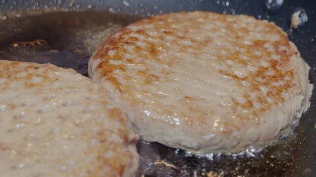 Hamburger patties frying and searing in hot skillet pan