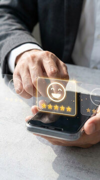 Hand using smartphone to rate service with happy face emoji and five stars, symbolizing excellent customer satisfaction and positive feedback