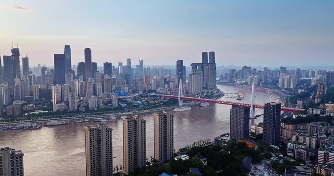 Aerial view of the city skyline and a bridge crossing the river at sunset in Chongqing, China