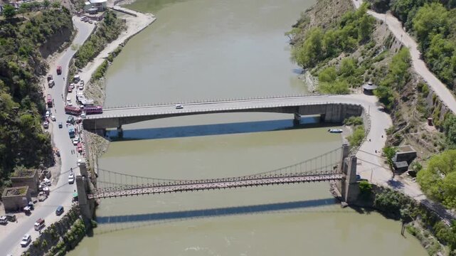 Sweeping drone shot of major bridge infrastructure crossing the Chenab River valley.