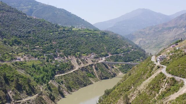 Aerial wide shot of a high concrete bridge crossing the Chenab River gorge in India.