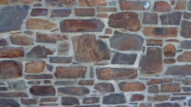 4K Slow Pan Across Rustic Natural Stone Wall Texture Background with Brown Rock Masonry
