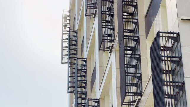 A modern high-rise building stands tall against a bright sunlit sky in Simferopol, Crimea. The neat rows of air conditioner cages look peaceful, creating a grand yet serene urban feeling.