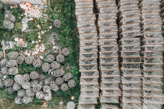 Aerial view of stacked crab pots and fishing buoys in a grassy area in Unalaska, Alaska, United States.