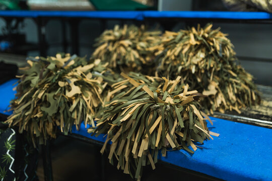 Finished handmade military camouflage ghillie helmets or covers placed on a blue surface.